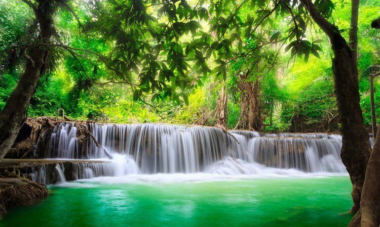 Thailand waterfall in Kanchanaburi, surrounded by lush greenery, creating a peaceful, serene atmosphere.